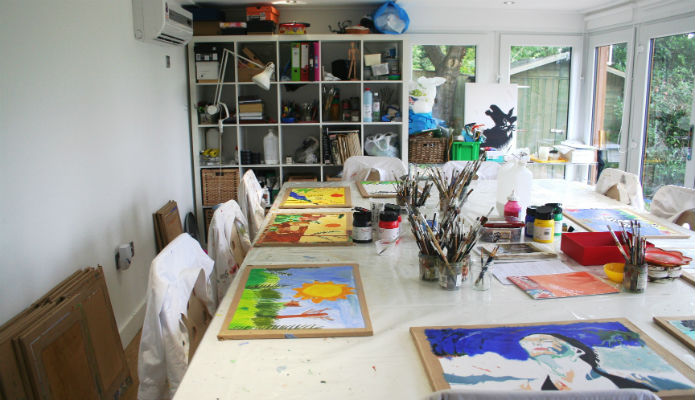 Large table within a garden room which is used for teaching young children how to paint